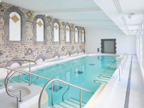 - une grande piscine dans un bâtiment avec un mur en briques dans l'établissement Appartement T2 - RDC à 300M des thermes - La villa blanche, à Le Mont-Dore