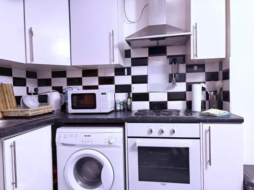 a kitchen with a stove microwave and a washer at Cozy flat in High Wycombe