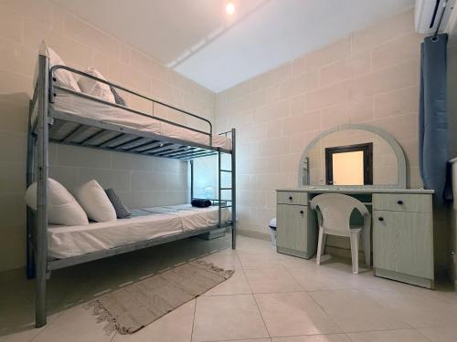 a bedroom with a bunk bed and a desk at Seashell Stories - Modern Comforts, Traditional Charm in Nadur