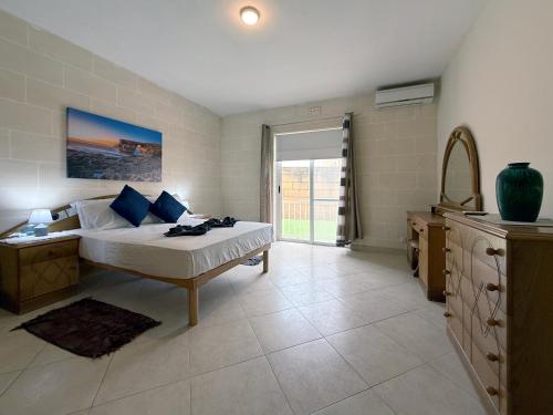 a bedroom with a bed and a dresser and a window at Seashell Stories - Modern Comforts, Traditional Charm in Nadur