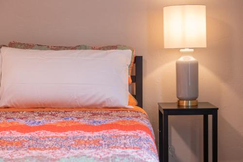 a bed with a white pillow and a lamp on a table at Plaza Pad I - New Apartment Near Plaza District in Oklahoma City