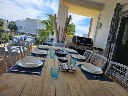 a wooden table with plates and bowls and glasses on it at La Cala Golf Resort Luxury appartment in Mijas