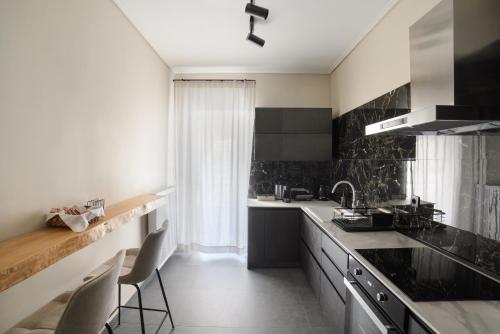 Una cocina con fregadero y una encimera con sillas. en Luxury Lounge Apartment, en Tríkala