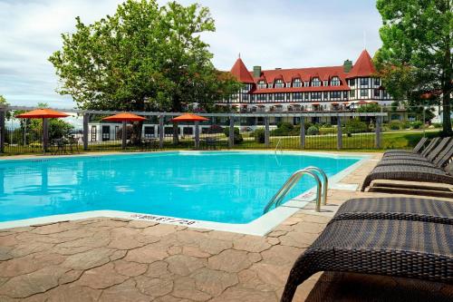 a swimming pool with benches and a hotel in the background at The Algonquin Resort St. Andrews by-the-Sea, Autograph Collection in Saint Andrews
