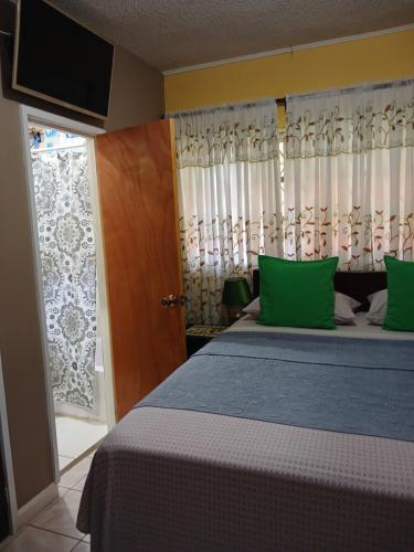 a bedroom with a bed with green pillows and a window at Ultimate Freedom Bed and Breakfast in Santa Cruz