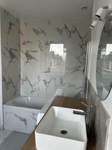 La salle de bains blanche est pourvue d'un lavabo et d'une baignoire. dans l'établissement Beau studio lumineux, à Mons-en-Baroeul