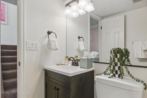 a bathroom with a sink and a toilet and a mirror at Spacious 4BD - Backyard BBQ, Fire Pit & Mini Golf in Arvada