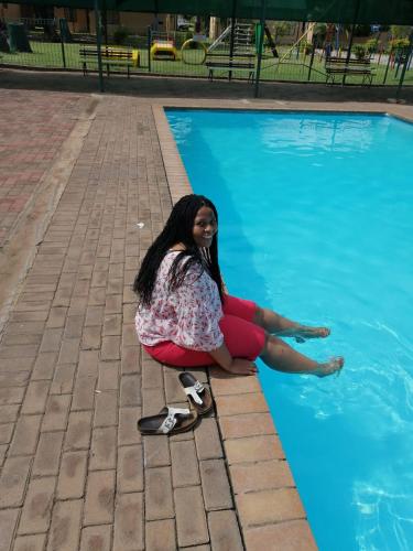 a woman sitting on a skateboard next to a swimming pool at 86 Pendleberry Holiday Grove in Warmbaths