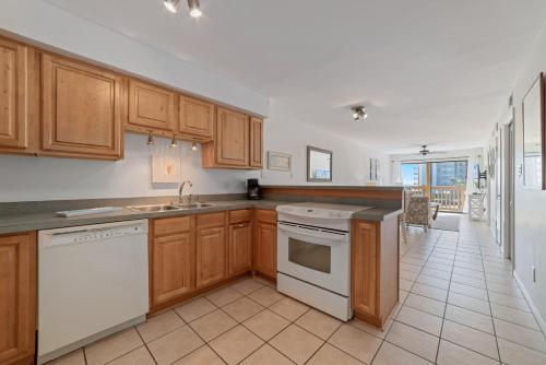 a kitchen with wooden cabinets and white appliances at Lei Lani Minit Tower Unit 219 in Orange Beach