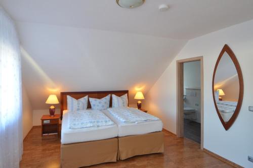 a bedroom with a large bed and a mirror at Land-Hotel Am Wald Garni in Greiz