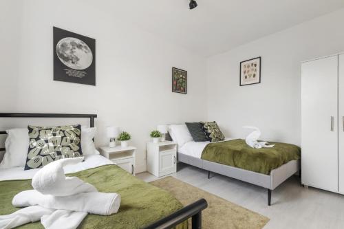 two beds in a room with white walls at Modern House with Free Parking near Wembley in London