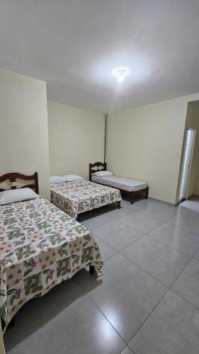 a room with two beds and a table in it at Pousada Morada do Sol AP 01 in Três Marias