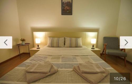 a bedroom with a bed with two lamps and a chair at Cozy Apartment Near Holiday Inn in Tbilisi City