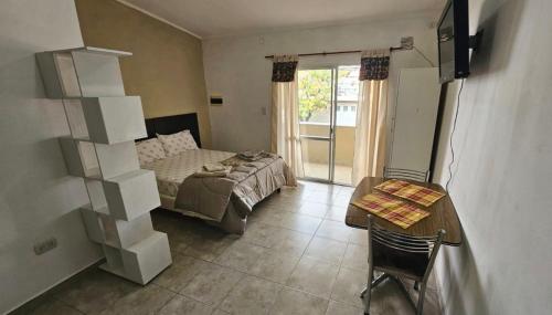 a bedroom with a bed and a table and a desk at Departamento Pellegrini in San Pedro