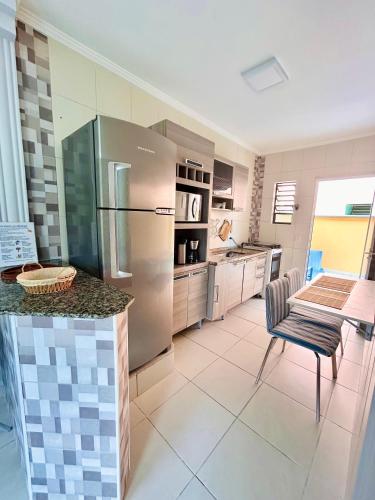 a kitchen with a stainless steel refrigerator and a table at Apê Ubahê Maranduba Ubatuba in Ubatuba