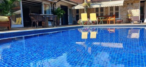 a blue swimming pool with a table and chairs at Pousada Boutique Itaipava in Itaipava