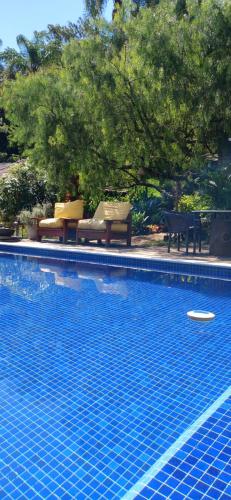 a swimming pool with two chairs and a frisbee in it at Pousada Boutique Itaipava in Itaipava