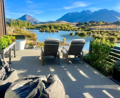 a patio with two chairs and a view of a lake at Tranquil Luxury on Willow Pond in Queenstown