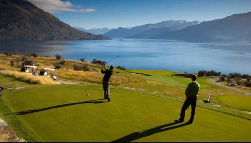 two people playing golf on a green with a lake at Tranquil Luxury on Willow Pond in Queenstown