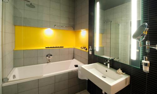a bathroom with a tub and a sink and a mirror at Hotel AquaCity Mountain View in Poprad