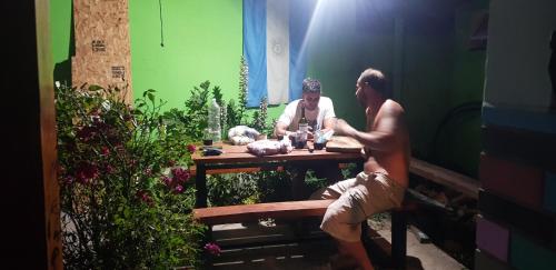 two men sitting at a table in a garden at La Estacion Hostel in Lago Puelo