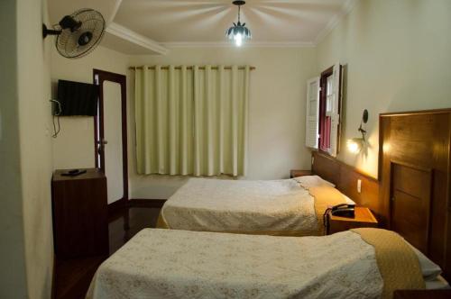 a hotel room with two beds and a window at Pousada dos Bandeirantes in Ouro Preto