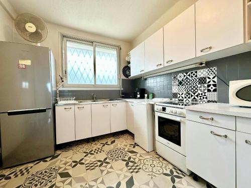  La cuisine est équipée de placards blancs et d'un réfrigérateur. dans l'établissement Nice 1 bedroom, sea view, 10 min from Cannes Center & Palais des Festivals, à Cannes