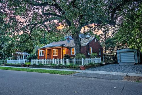 a brown house with a white fence and a tree at Delsey family home steps away from Park Circle in Charleston