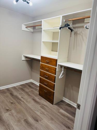 a walk in closet with white shelves and a wooden drawer at The home away from home in Greensboro