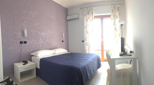 a bedroom with a blue bed and a window at Hotel Piccolo Paradiso in Bordighera