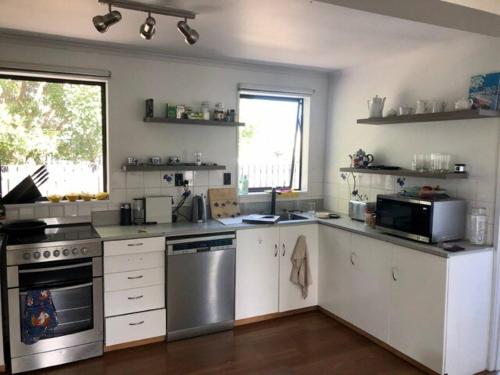 Una cocina con gabinetes blancos y electrodomésticos de acero inoxidable. en South Bay Haven, en Kaikoura