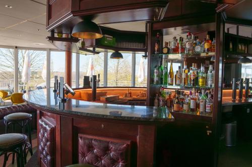 a bar in a restaurant with a lot of bottles at L'Hôtel et Restaurant du Golf de Clervaux in Eselborn