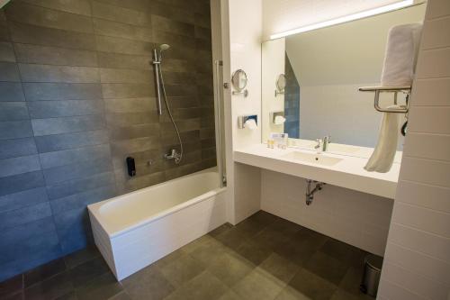 a bathroom with a tub and a sink and a shower at L'Hôtel et Restaurant du Golf de Clervaux in Eselborn
