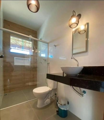 a bathroom with a sink and a toilet and a mirror at Chalé Alta Vista Acuruí in Itabirito