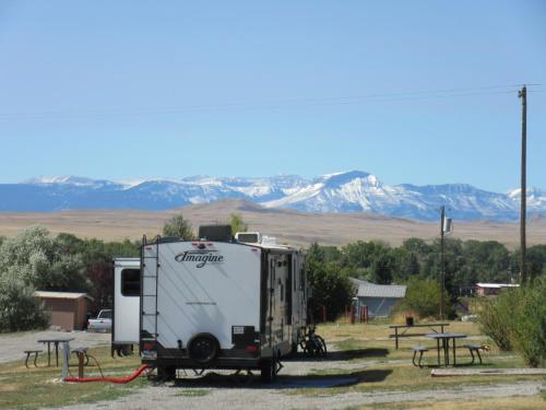 a white trailer parked in a parking lot with mountains in the background at Choteau Mountain View RV Campground in Choteau
