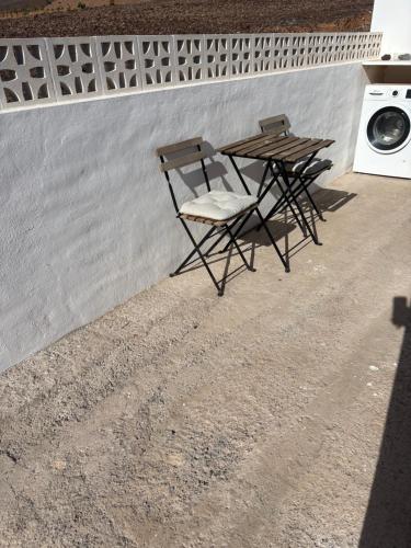 two chairs and a table next to a wall at Los Marmoles in Giniginámar