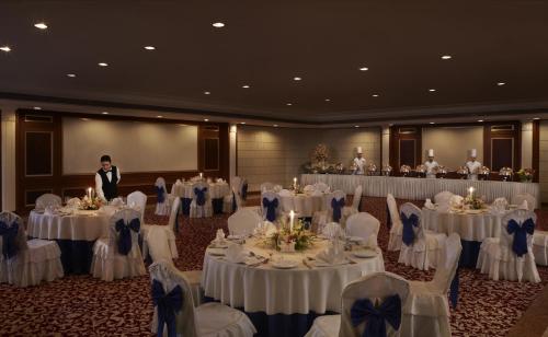 a man standing in front of a room filled with tables and chairs at Hotel The Royal Plaza in New Delhi
