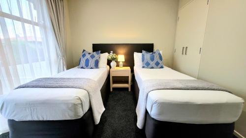 two twin beds in a room with a window at TOWER JUNCTION MOTOR LODGE- MOTEL with Airport and Railway Station Shuttle service- Best Location - close to Westfield Mall, Tower Junction Shopping Centre, Restaurants, Cafes etc in Christchurch
