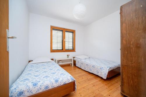 a bedroom with two beds and a window at Secluded fisherman's cottage Zman, Dugi otok - 19000 in Žman