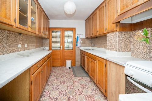 a kitchen with wooden cabinets and white counter tops at Secluded fisherman's cottage Zman, Dugi otok - 19000 in Žman