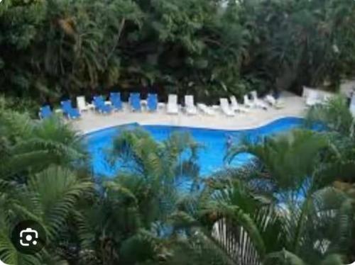 a swimming pool with blue chairs and palm trees at Cozy Marbella suits 2 bed 2 bath in Puerto Vallarta