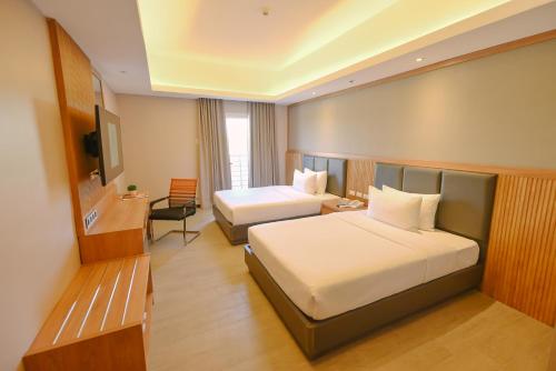 a hotel room with two beds and a television at Sotogrande Hotel and Convention Center Batangas in Bauan