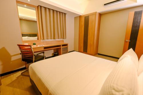 a hotel room with a bed and a desk and a desk at Sotogrande Hotel and Convention Center Batangas in Bauan