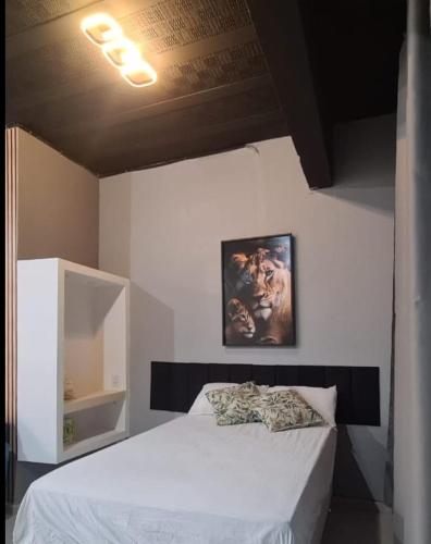 a bedroom with a white bed and a painting on the wall at Aconchego II - Centro in Miguel Pereira