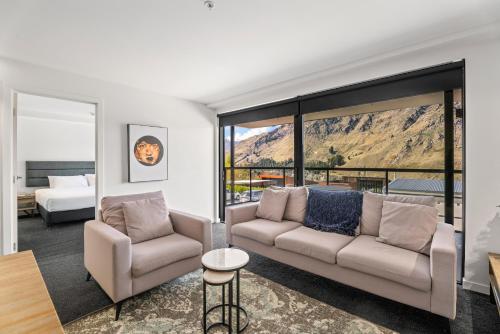 ein Wohnzimmer mit einem Sofa, einem Bett und Fenstern in der Unterkunft Residence du Parc by Staysouth in Queenstown