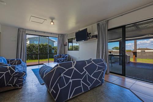 a living room with a couch and a large window at Virtue Escape - Beachside Bliss at Tokerau Beach in Kaitaia