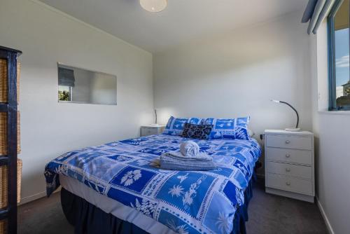 a bedroom with a bed with a blue and white bedspread at Virtue Escape - Beachside Bliss at Tokerau Beach in Kaitaia