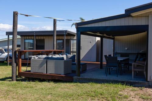 a patio with a couch and a table and chairs at Virtue Escape - Beachside Bliss at Tokerau Beach in Kaitaia