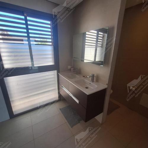 Un baño con lavabo, espejo y ventana. en Sea Breese Golf & Ocean view Taghazout Bay Amda, en Taghazout