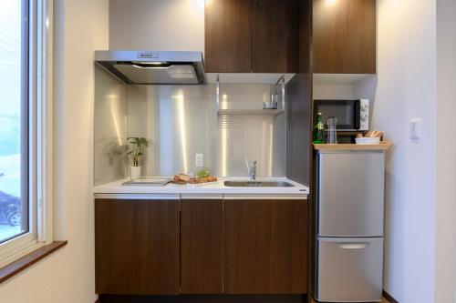 a small kitchen with a sink and a microwave at SnowDog Village in Niseko